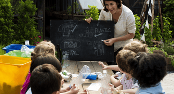 A teacher explains different recyclable material to a group of studnets
